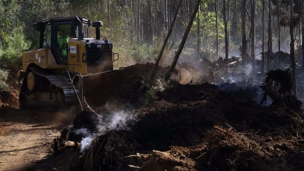 Un bulldózer trabajando en la zona arrasada por el fuego en Barreiros. JMª ÁLVEZ