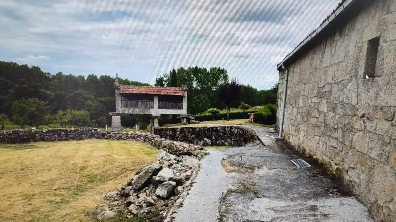 Un lateral del inmueble en venta con el hórreo centenario al fondo. IDEALISTA